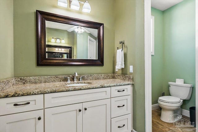 bathroom with baseboards, vanity, and toilet