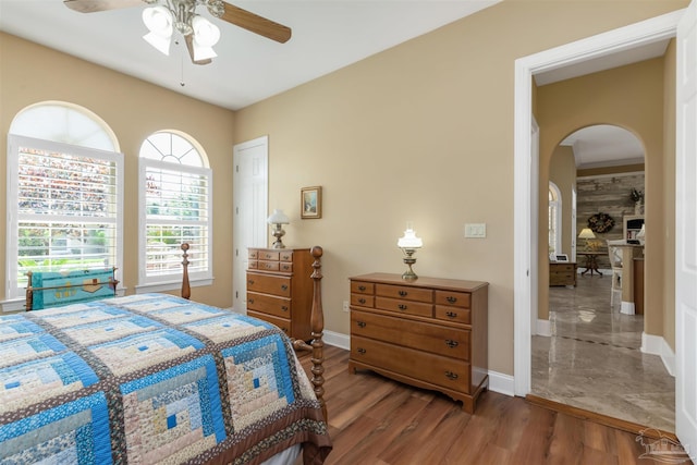 2792 Pga Blvd, Navarre, FL 32566 - bedroom featuring arched walkways, baseboards, a ceiling fan, and wood finished floors