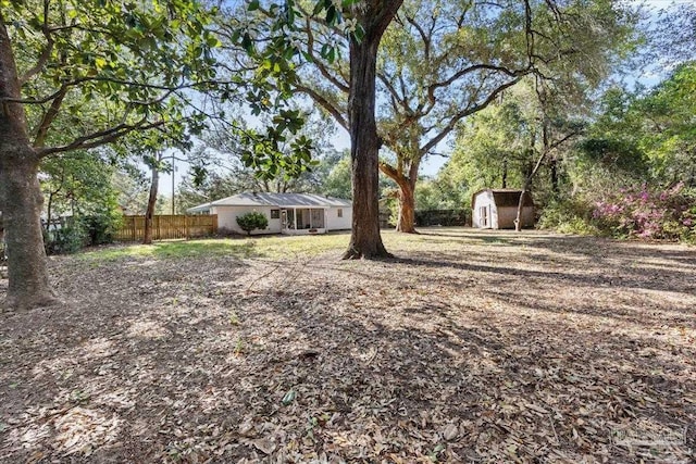 view of yard featuring fence, an outdoor structure, and a shed