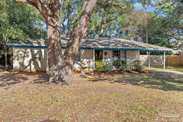 ranch-style home featuring brick siding, a carport, and fence