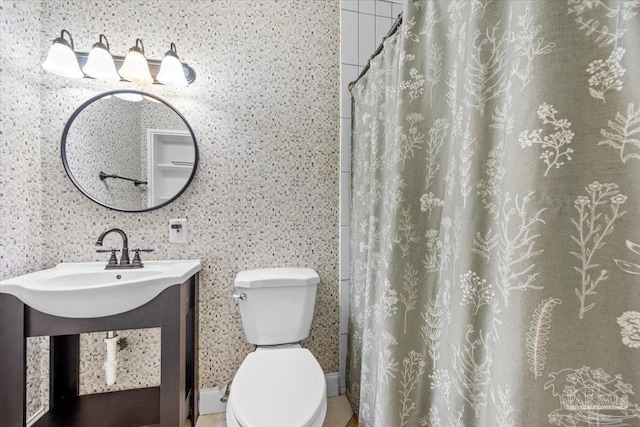 bathroom featuring curtained shower, toilet, and a sink