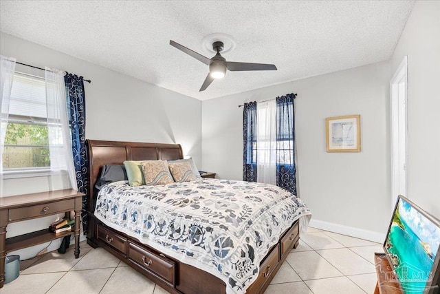 bedroom with ceiling fan, light tile patterned floors, baseboards, and a textured ceiling