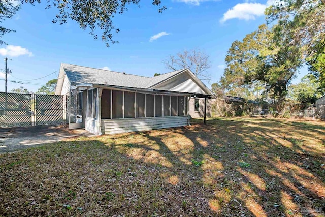 back of property with a sunroom and a lawn