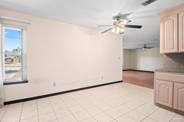 empty room with ceiling fan and light tile patterned floors