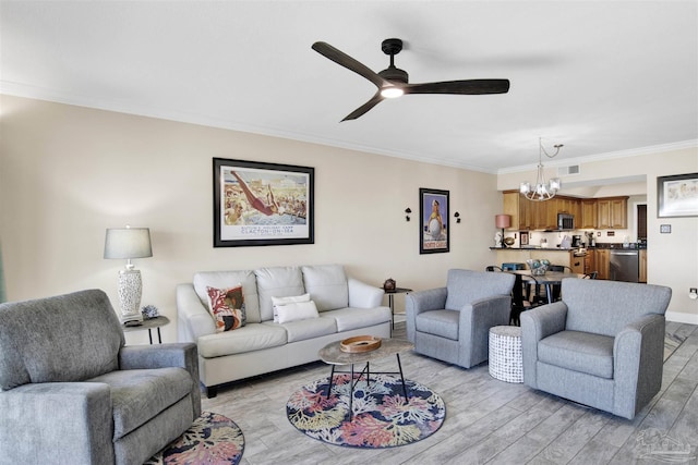 living room with ceiling fan with notable chandelier, light hardwood / wood-style floors, and crown molding