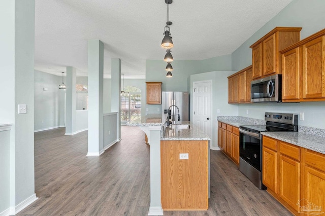 kitchen featuring light stone counters, sink, a center island with sink, and appliances with stainless steel finishes