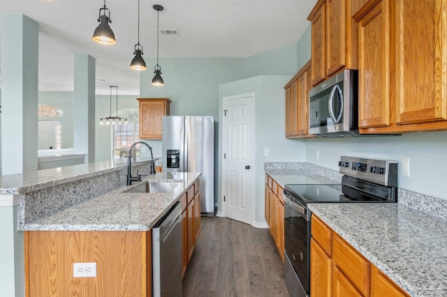 kitchen with appliances with stainless steel finishes, sink, an island with sink, and hanging light fixtures