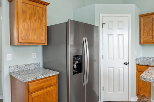 kitchen featuring light stone countertops and stainless steel fridge with ice dispenser