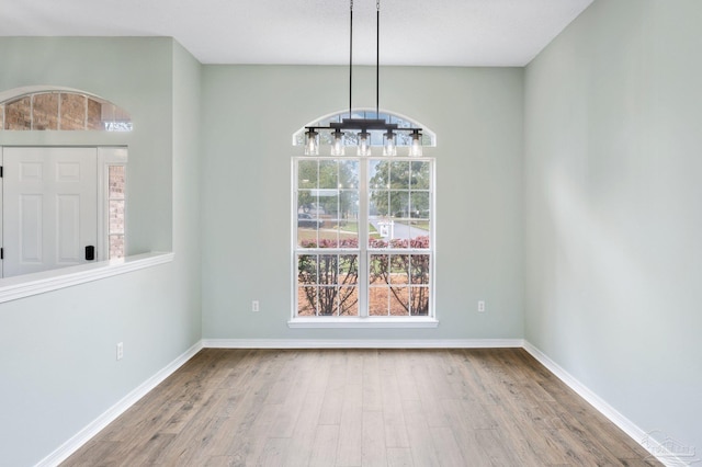 unfurnished dining area with hardwood / wood-style flooring and a chandelier