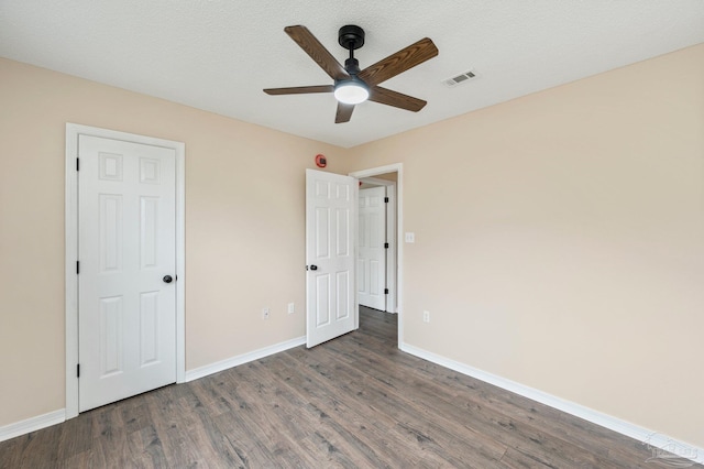 unfurnished bedroom featuring ceiling fan, dark wood-type flooring, and a textured ceiling