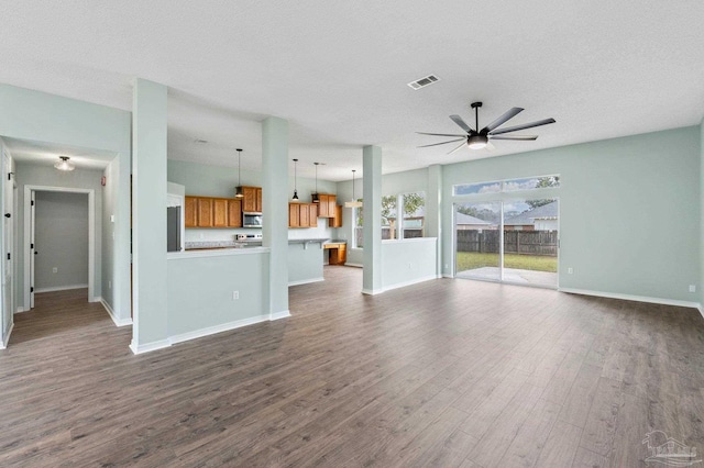 unfurnished living room featuring a textured ceiling, dark wood-type flooring, and ceiling fan