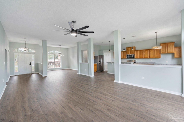 unfurnished living room with ceiling fan with notable chandelier, dark hardwood / wood-style floors, and a textured ceiling