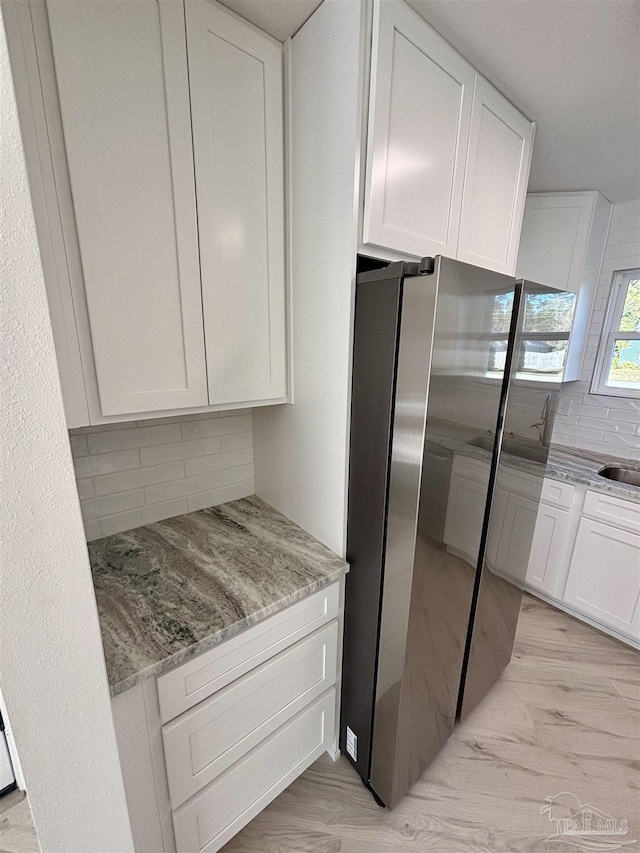 kitchen with white cabinets, light stone countertops, sink, and tasteful backsplash