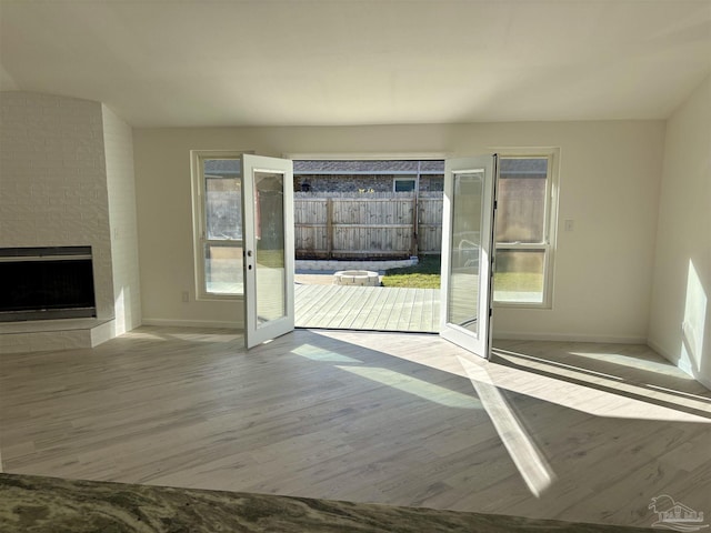 interior space with a fireplace, french doors, and light wood-type flooring