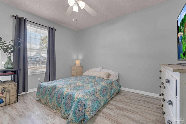 bedroom featuring ceiling fan, a textured ceiling, and light wood-type flooring