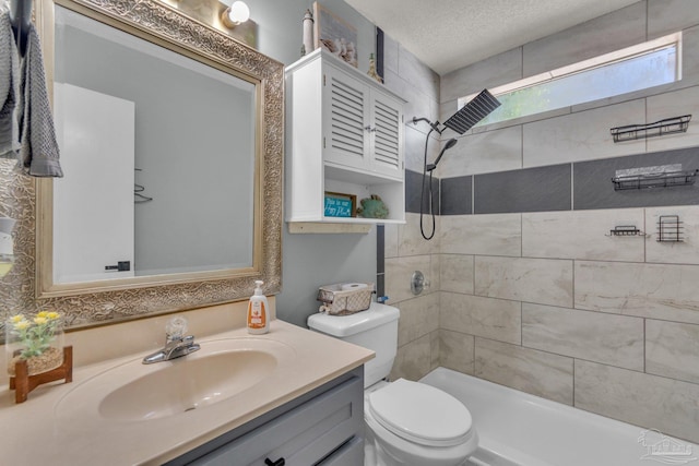 bathroom with vanity, tiled shower, a textured ceiling, and toilet