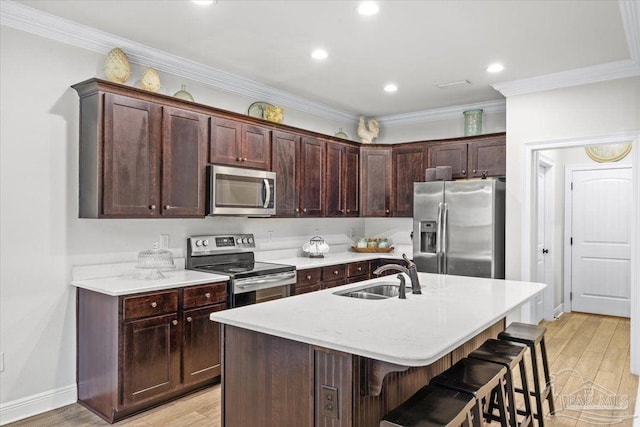 2219 River Birch Rd, Gulf Breeze, FL 32563 - kitchen with stainless steel appliances, a sink, a breakfast bar area, light wood-type flooring, and a kitchen island with sink
