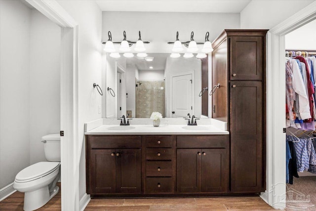 2219 River Birch Rd, Gulf Breeze, FL 32563 - full bathroom featuring a stall shower, double vanity, a walk in closet, wood finished floors, and toilet
