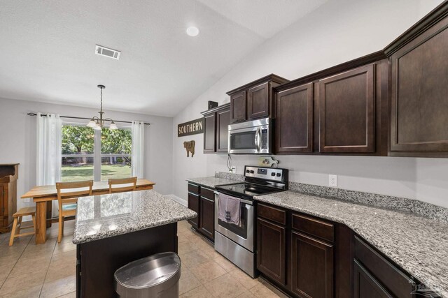 5613 Cane Syrup Cir, Pace, FL 32571 - kitchen with stainless steel appliances, lofted ceiling, dark brown cabinets, light stone counters, and light tile patterned flooring