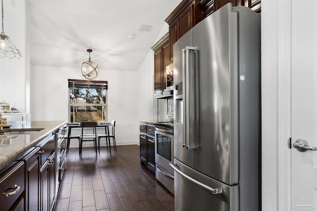 kitchen featuring sink, light stone counters, decorative light fixtures, dark brown cabinets, and appliances with stainless steel finishes