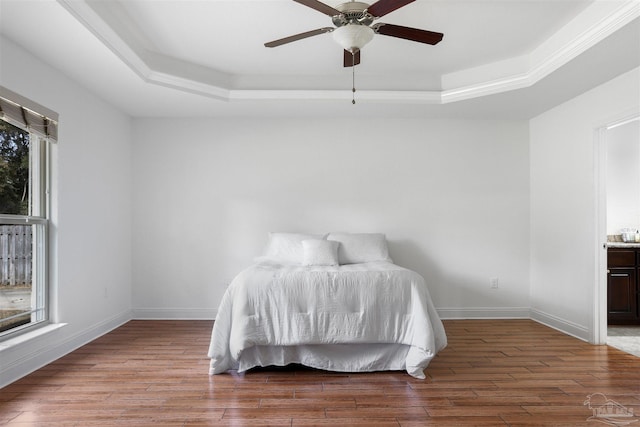 bedroom with a raised ceiling, hardwood / wood-style floors, and ceiling fan