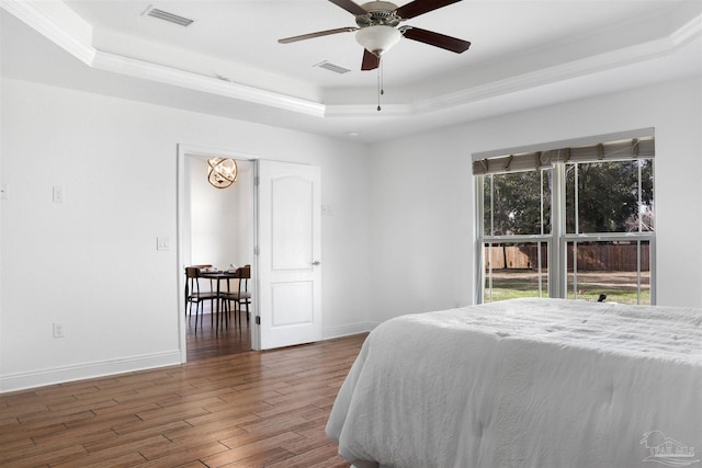 bedroom featuring dark hardwood / wood-style floors, a raised ceiling, and ceiling fan