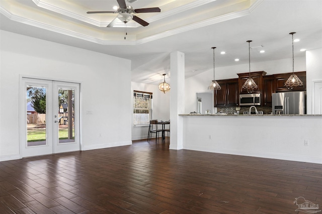 unfurnished living room featuring dark wood-type flooring, a healthy amount of sunlight, and a raised ceiling