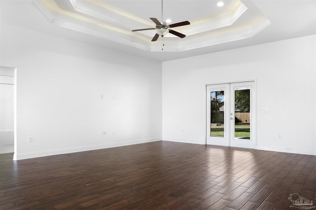 spare room with a raised ceiling, ornamental molding, dark wood-type flooring, and french doors