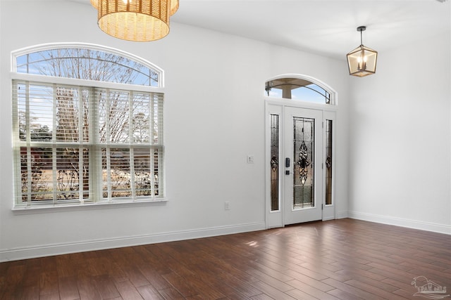 entryway with an inviting chandelier and dark wood-type flooring