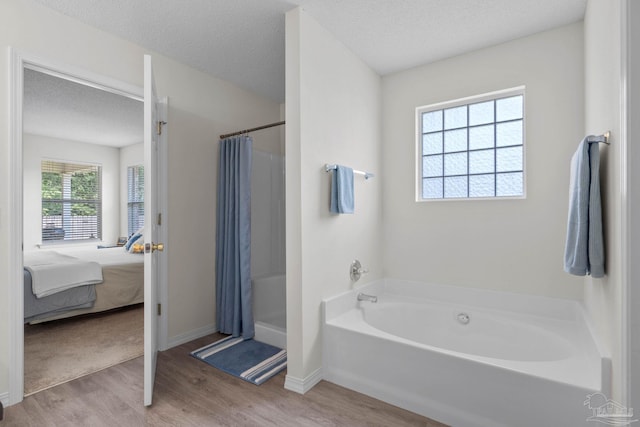 6742 Britt St, Navarre, FL 32566 - bathroom with wood finished floors, a stall shower, a bath, connected bathroom, and a textured ceiling