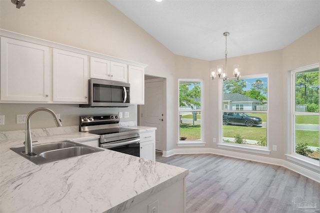 kitchen featuring stainless steel appliances, vaulted ceiling, white cabinets, sink, and light wood-type flooring