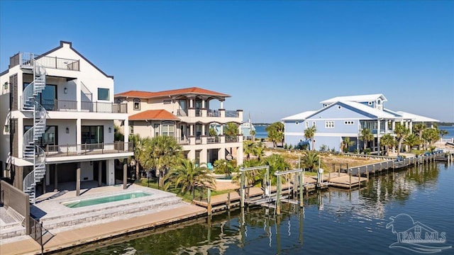 view of dock with a balcony, a patio, an in ground hot tub, and a water view