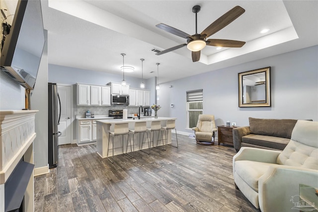 living area featuring a ceiling fan, dark wood-style floors, recessed lighting, a tray ceiling, and baseboards