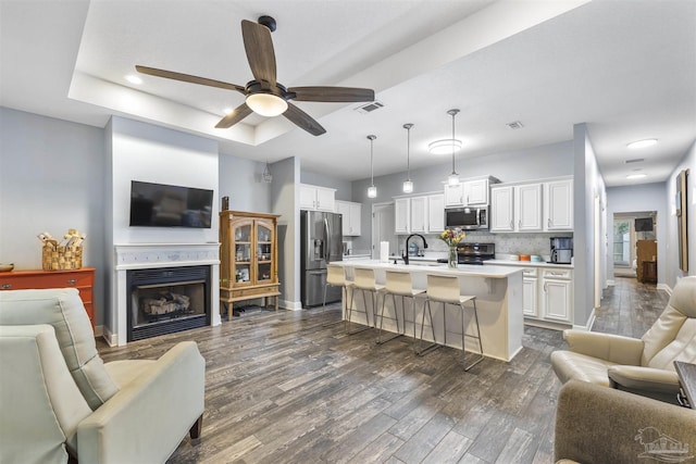 living room featuring dark wood finished floors, ceiling fan, a fireplace, and baseboards