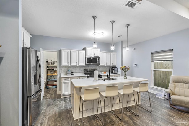 kitchen featuring appliances with stainless steel finishes, dark wood-style flooring, light countertops, and backsplash