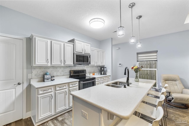 kitchen featuring stainless steel appliances, a sink, a breakfast bar area, tasteful backsplash, and light countertops