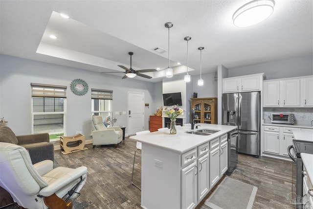 kitchen featuring appliances with stainless steel finishes, a sink, open floor plan, dark wood-style floors, and a ceiling fan