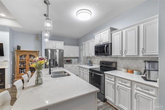 kitchen featuring appliances with stainless steel finishes, a sink, dark wood-style floors, tasteful backsplash, and decorative light fixtures