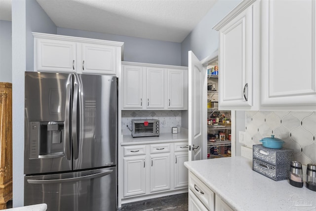 kitchen featuring stainless steel fridge with ice dispenser, white cabinetry, and tasteful backsplash
