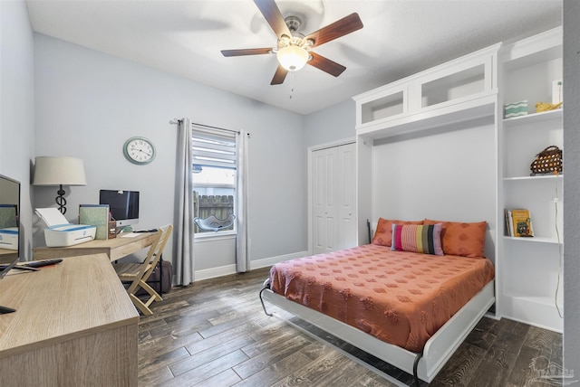 bedroom featuring dark wood-type flooring, a desk, baseboards, a ceiling fan, and a closet