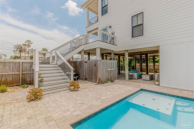 rear view of property featuring stairs, board and batten siding, a fenced backyard, a patio area, and a balcony