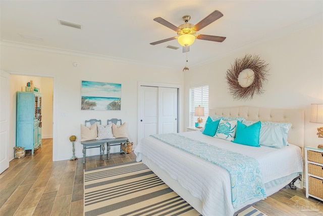 bedroom featuring visible vents, crown molding, wood finished floors, and a closet