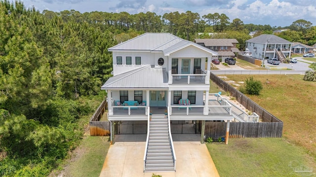 back of property with a lawn, a carport, a balcony, and concrete driveway