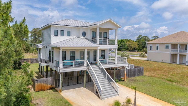 coastal inspired home with covered porch, a front yard, a carport, a balcony, and concrete driveway
