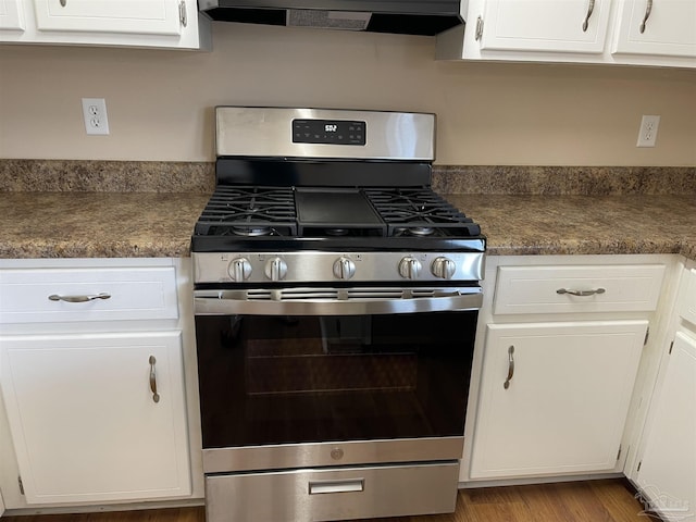 kitchen featuring extractor fan, stainless steel gas range, and white cabinets