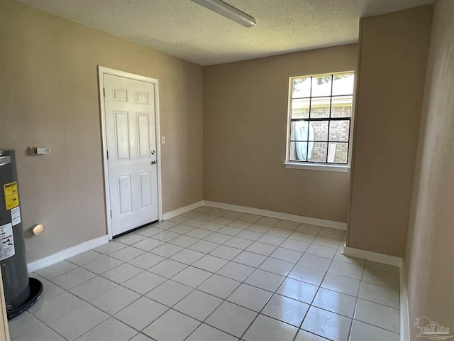 tiled spare room with electric water heater and a textured ceiling