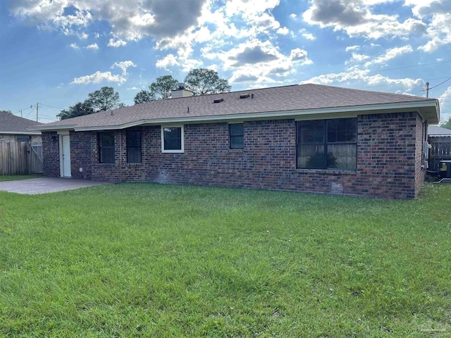 rear view of property featuring a lawn and a patio area