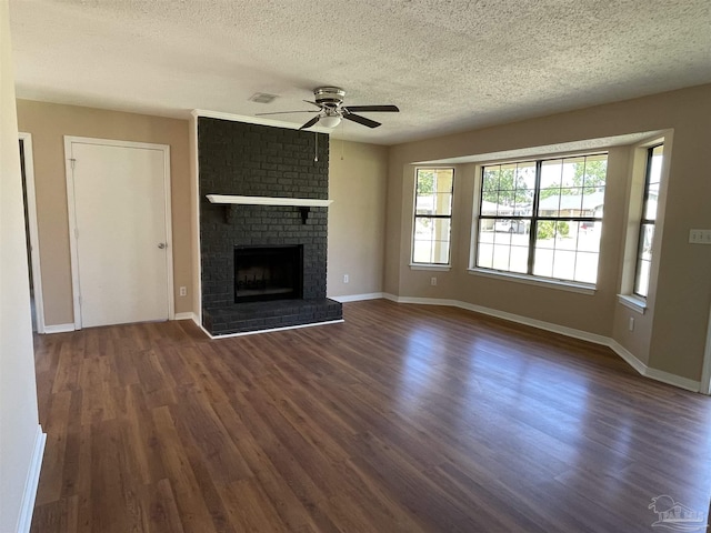 unfurnished living room featuring dark hardwood / wood-style flooring, ceiling fan, a fireplace, and a textured ceiling