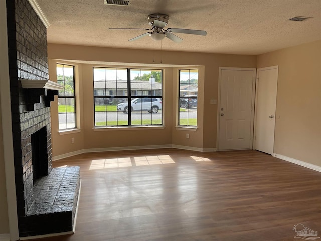 unfurnished living room with ceiling fan, a fireplace, a textured ceiling, and light wood-type flooring