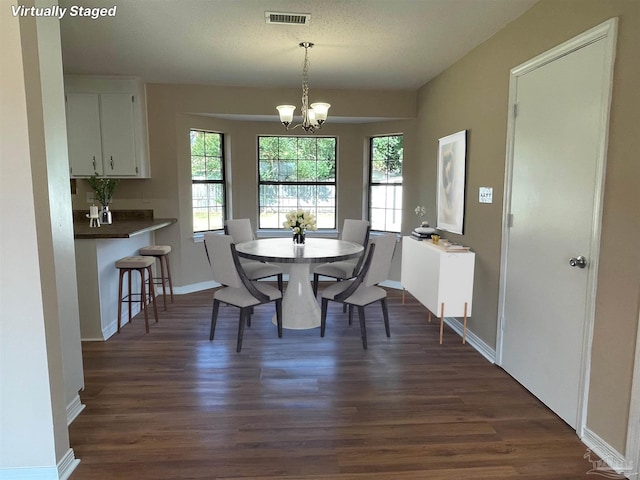 dining area with an inviting chandelier, dark hardwood / wood-style flooring, and a textured ceiling